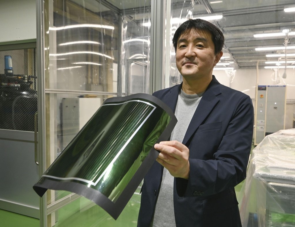ペロブスカイト太陽電池を手にするエネコート・テクノロジーズの加藤尚哉社長＝2023年9月、京都府久御山町（共同）