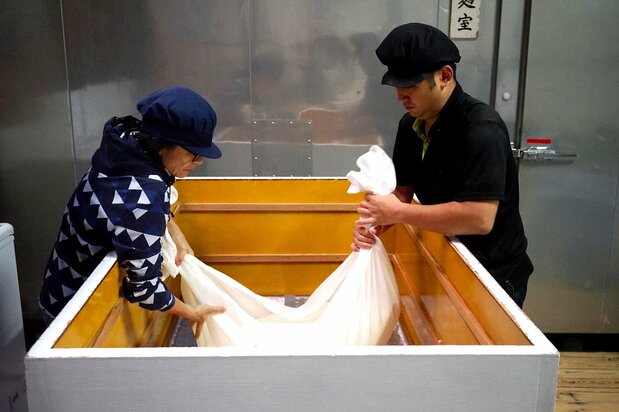 Imada et son assistant soulèvent le riz fermenté dans le kôji-muro, le saint des saints de la brasserie. C’est là où le riz est imprégné d’un champignon microscopique appelé kôji. C’est ce procédé de 48 heures qui détermine la qualité du saké.