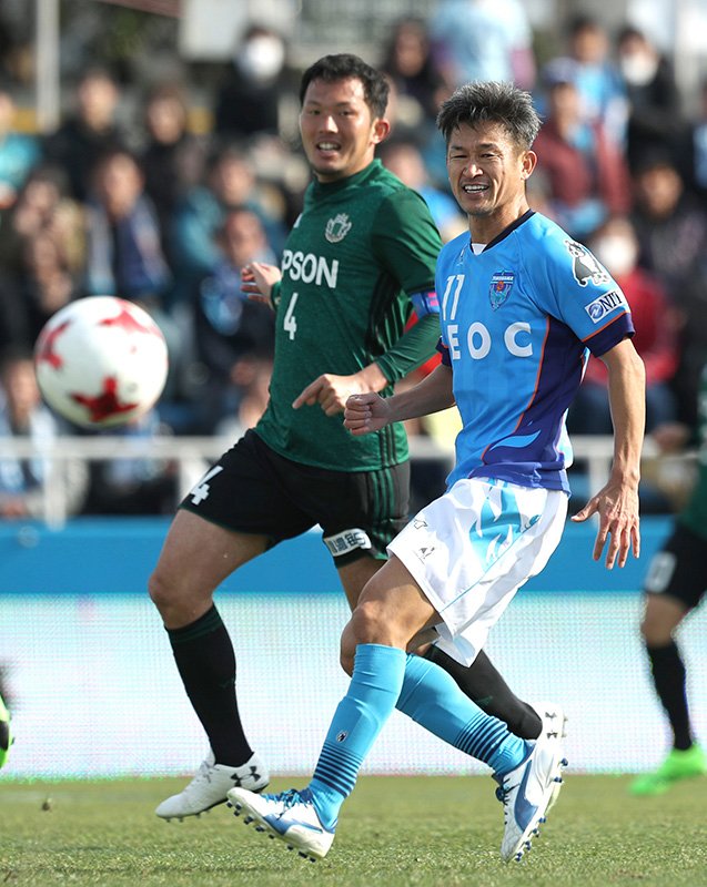 Игрок команды Yokohama FC Миура Кадзуёси (справа) в погоне за мячом в первой половине матча с командой Мацумото, 26 февраля, стадион Ниппацу Мицудзава (фотография предоставлена Jiji Press)