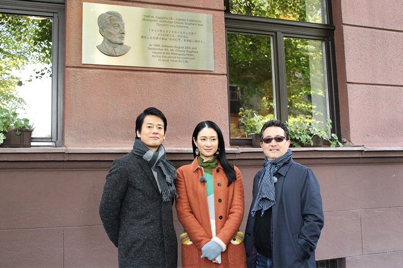 Karasawa Toshiaki, Koyuki y Gluck frente al hotel Metropolis de Kaunas, en el que se alojó Sugihara Chiune antes de abandonar Lituania. En este hotel Chiune continuó expidiendo visados tras el cierre del consulado, a finales de agosto de 1940. ©2015 Comité de Producción de Sugihara Chiune