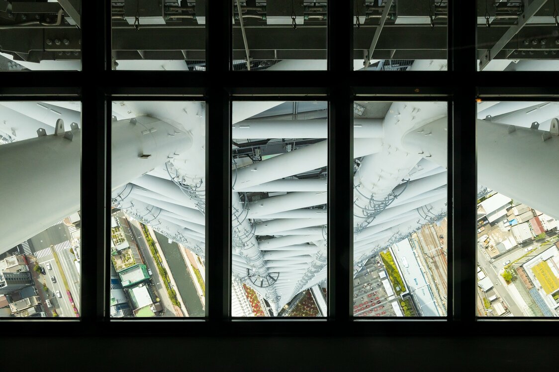 Desde el suelo de cristal del mirador en el piso 340 se puede observar cómo la base triangular, en el centro de la fotografía, va transformándose en un círculo. A los lados se pueden apreciar las curvas de la técnica mukuri.