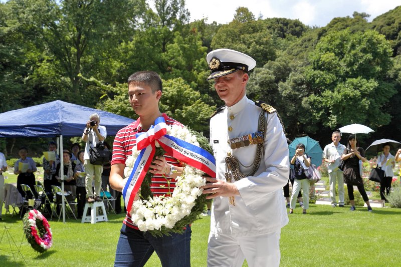 Morii Motoki, left, helps lay a wreath as other participants sing “Home, Sweet Home.”