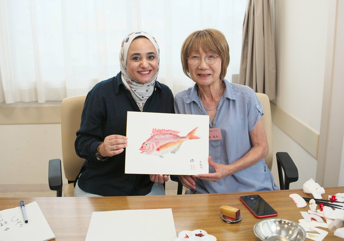 المعلم والتلميذة يقفان إلى جانب العمل المكتمل. (© نومورا كازويوكي)