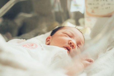 産婦人科のベッドで眠る赤ちゃん＝資料