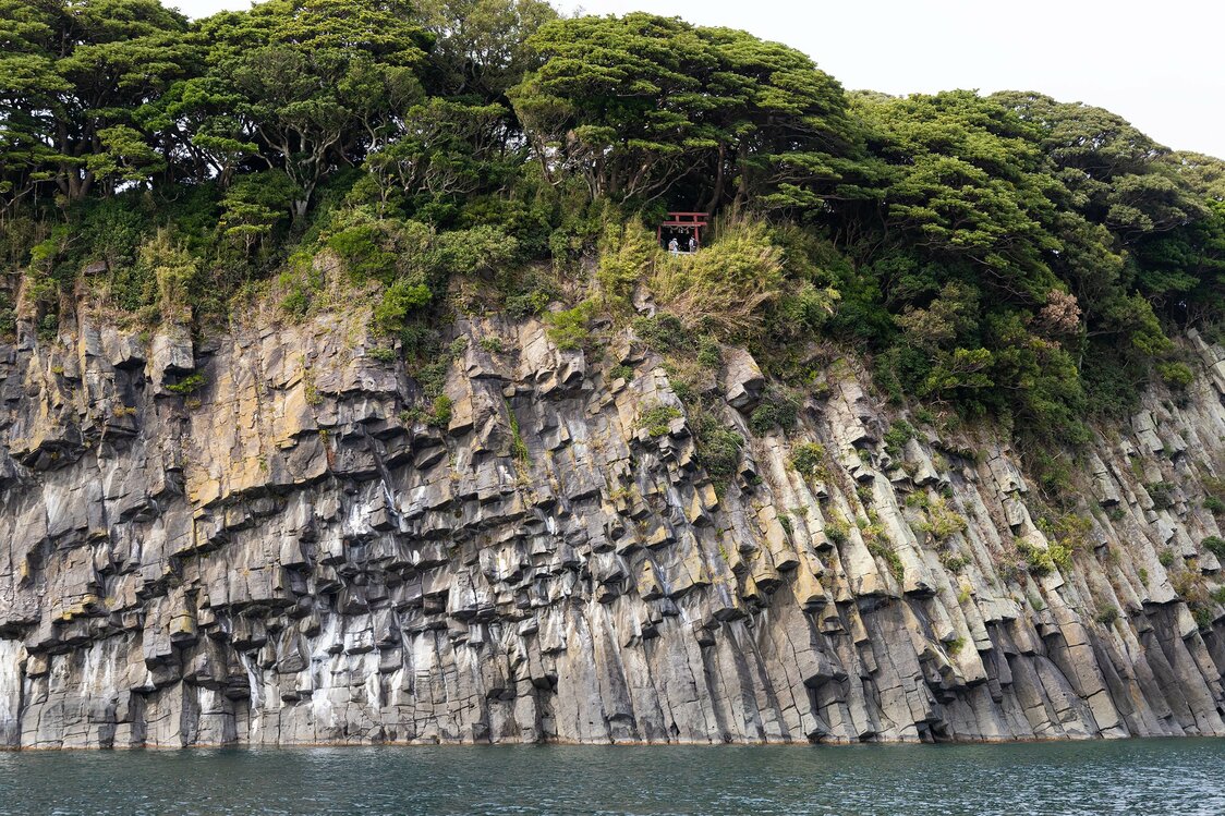 在“蜂巢岩”的崖壁上方，可以看到大凑神社的红色鸟居