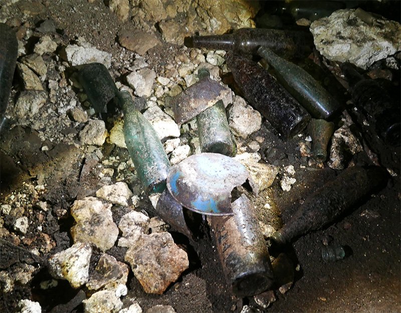 Différents objets toujours présents dans les grottes : bouteilles de bières, douilles, bandages, etc.