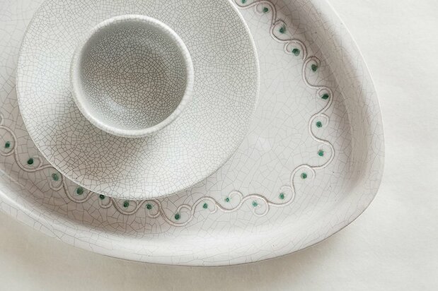 Cups and plates with a modern feeling brought about by the crazed effect in the white matt glaze.