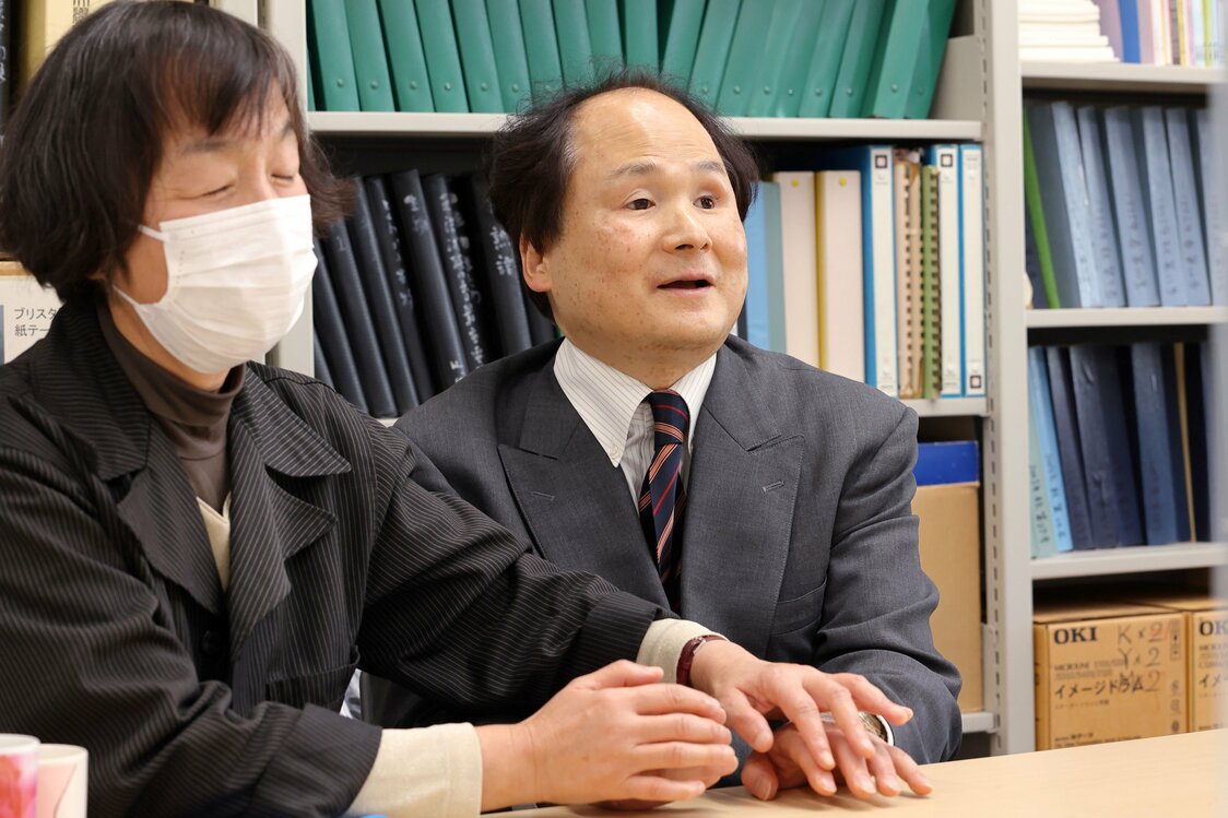 指点字の通訳（左、春野ももこさん）に指をタップしてもらい、対話相手の話を理解する福島教授