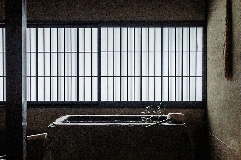 Agua para lavarse las manos en el suelo no entarimado del vestíbulo. A la izquierda, un hogar u hoguera doméstica, kamado en japonés, que se utiliza para elaborar miso, entre otros.