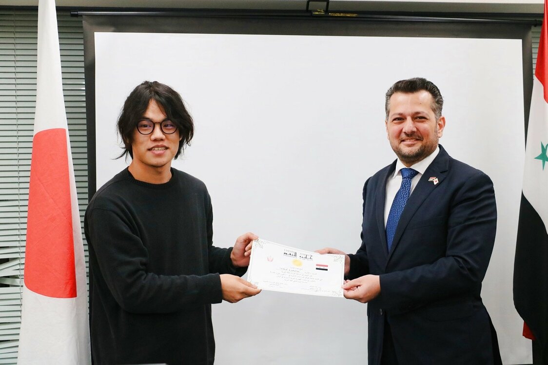 最優秀賞に選ばれた岡田祥寛さん。審査委員長を務めたムハンマド・ナジーブ・エルジー在日本シリア・アラブ共和国臨時代理大使から賞状を授与された