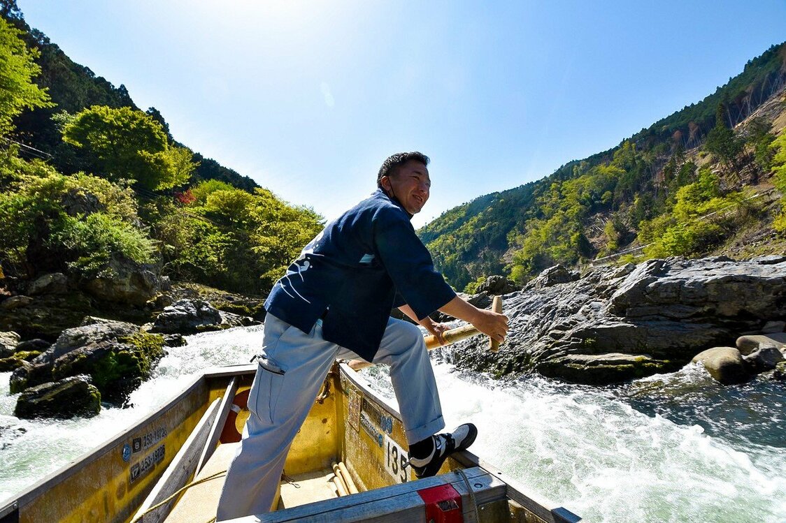 Notre pilote, debout vers la poupe, nous guide à travers les rapides tandis que deux membres de l’équipage utilisent des bâtons pour éviter les rochers.