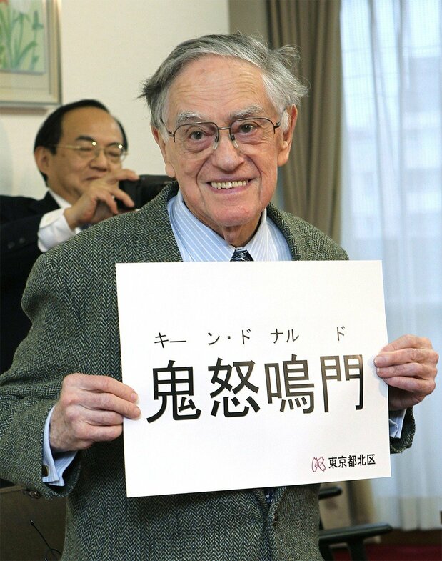 Donald Keene shows reporters his official Japanese name in kanji in Tokyo on March 8, 2012, after taking Japanese citizenship. In the background is his adopted son Seiki. (© Jiji)
