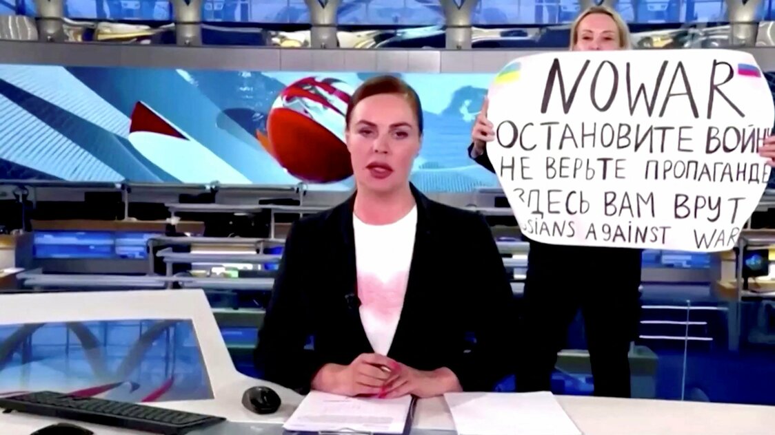 ロシア国営テレビのニュース放送時間中に「戦争反対」の手書きの紙を掲げる女性（ロイター）