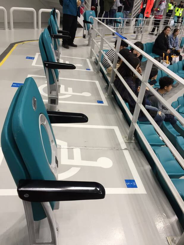 Asientos para sillas de ruedas en la pista de hockey de Pieonchang. Las plazas para sillas de ruedas se alternan con asientos fijos.