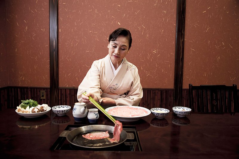 The waitress makes sure that each piece of beef is cooked to perfection.