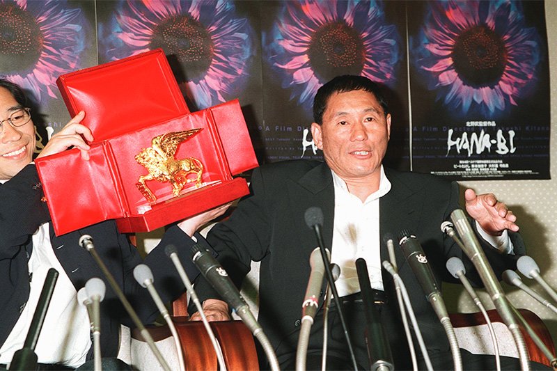 Le 9 septembre 1997, lors de la conférence de presse qu’il a donné à l’aéroport de Narita à son retour de la Mostra de Venise où il avait obtenu le Lion d’Or pour Hanabi (Jiji Press)
