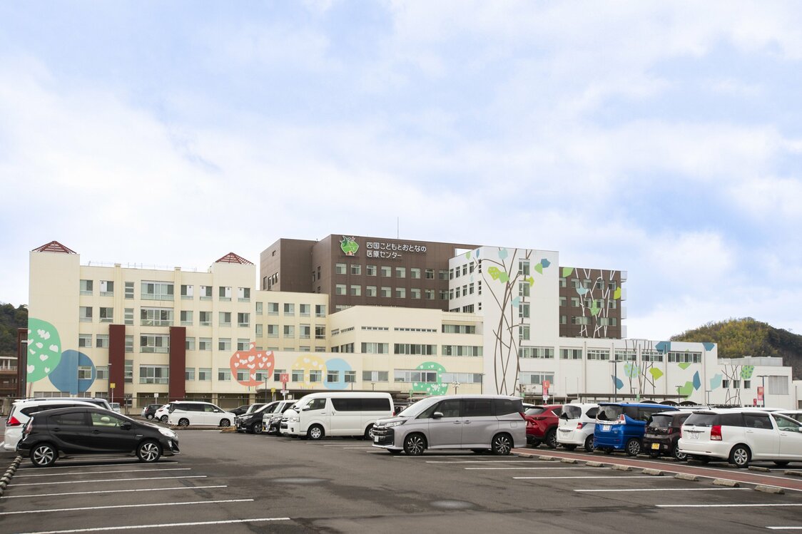Vue extérieure du Centre médical de Shikoku pour enfants et adultes. Sur les murs du bâtiment sont dessinés de jeunes arbres et des feuillages colorés rappelant ceuxpeints le long des couloirs par les patients et les soignants de l’hôpital pour enfants de Kagawa.