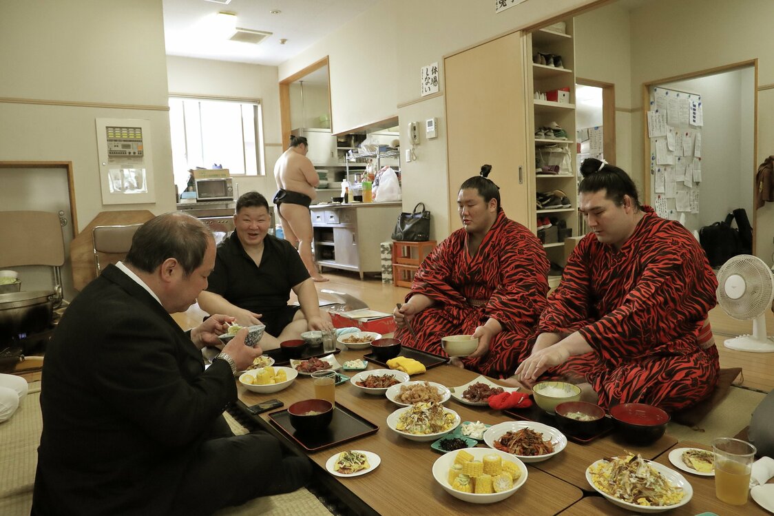 親方と関取から食べ始め、時には後援会のメンバーや稽古の見学客と食卓を囲むこともある。この日は部屋所属の三役行司・式守勘太夫さん（左）が顔を見せた