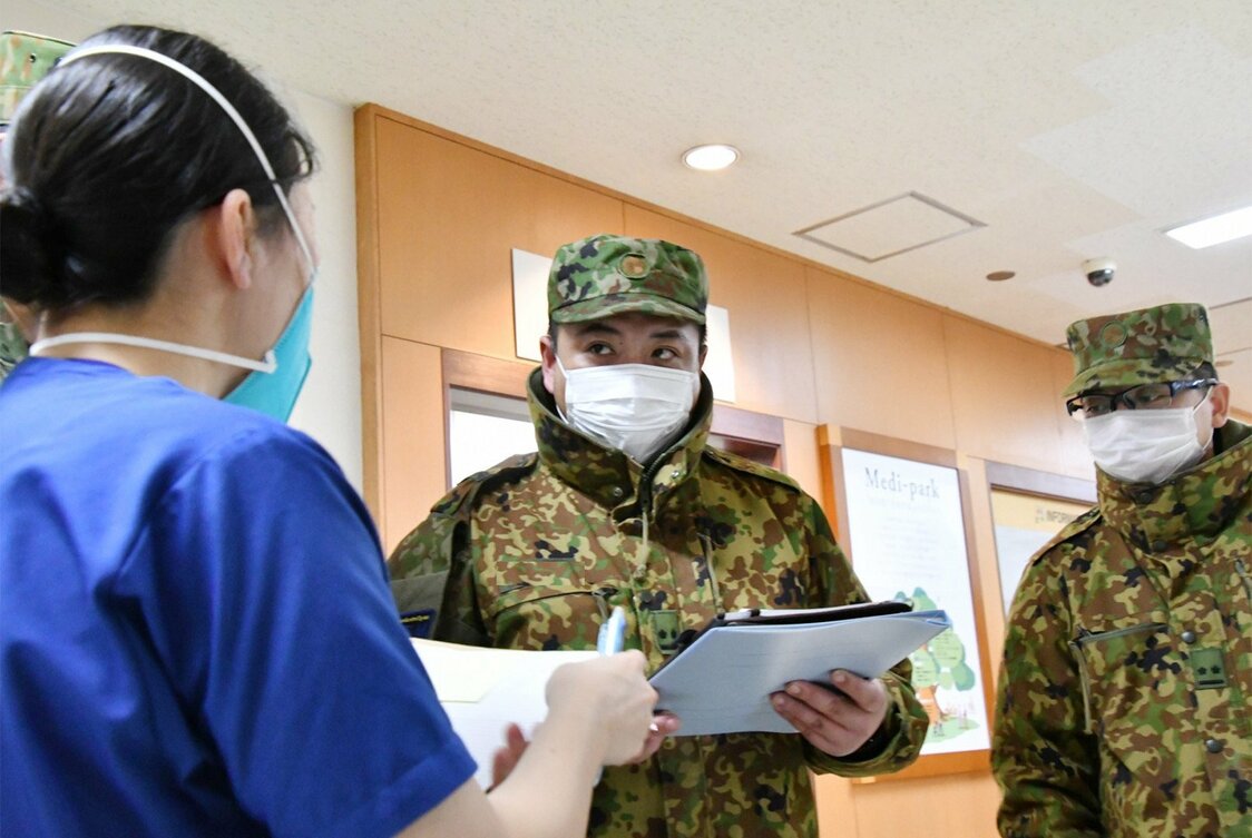 災害派遣された慶友会吉田病院内（北海道旭川市）で、陸上自衛隊の看護師（看護官）（左）と医療支援の打ち合わせをする隊員＝防衛省統合幕僚監部提供（時事）