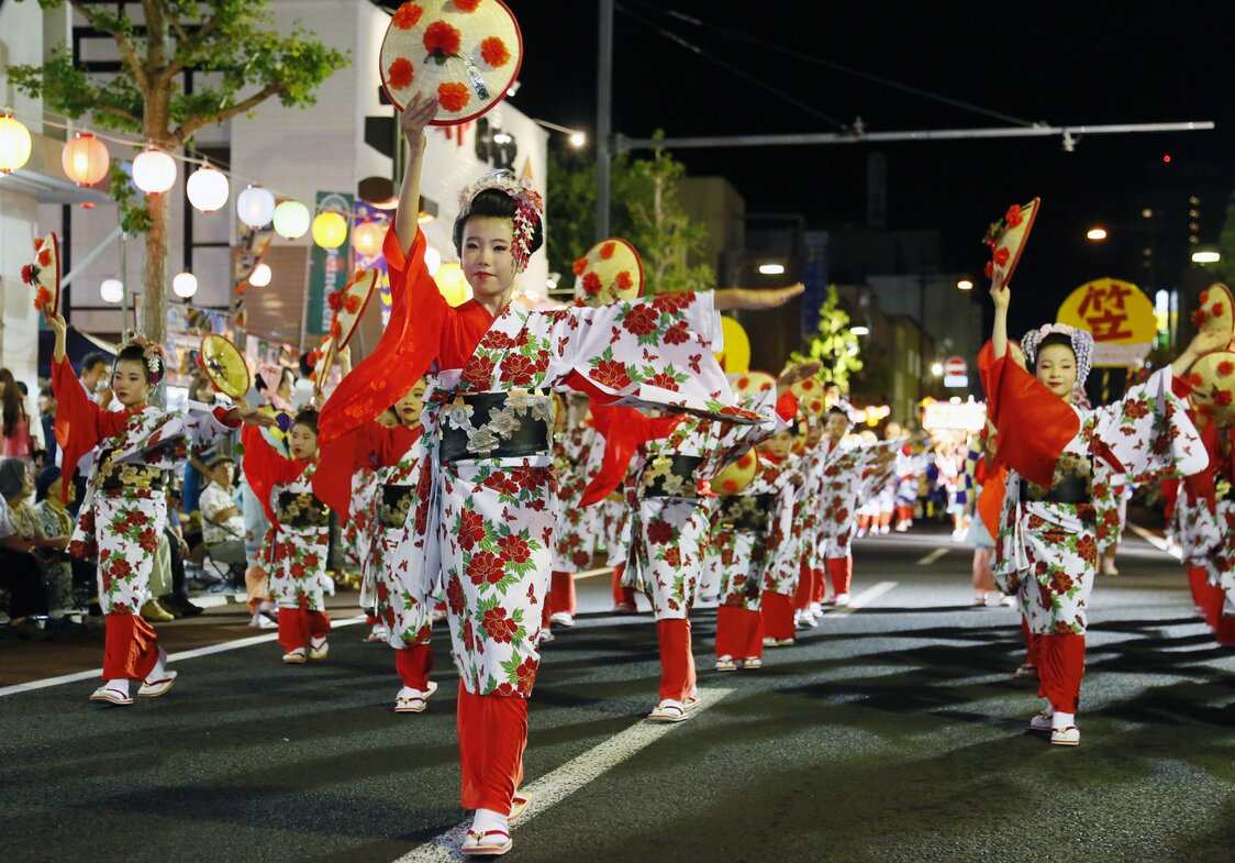 Dancers move in perfect unison to tunes singing the praises of local places and specialties. (© Haga Library)