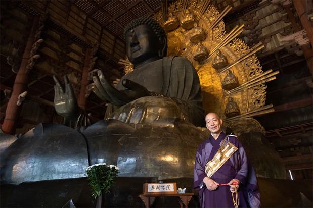 Chief Abbot Hashimura Kōei standing with the Daibutsu. (© Muda Haruhiko)