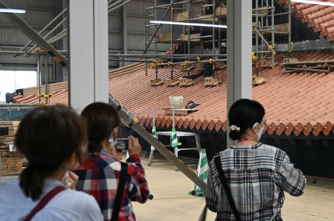 見学スペースから首里城正殿の復元工事を見る人たち（時事）