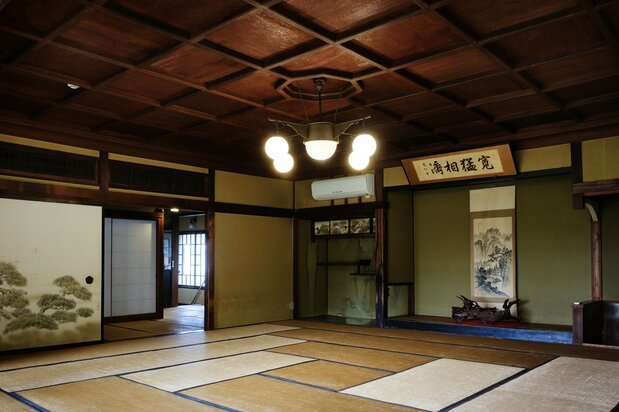 銘木が使われた床の間。「寛猛相済(かんもうそうさい)」の額は、皇族でありながら陸軍大将として活躍した閑院宮載仁(ことひと)親王から現当主の曽祖父が拝領したもの