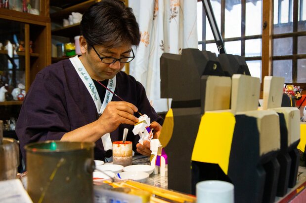 店舗の片隅で、三春駒の絵柄を描く彰一さん