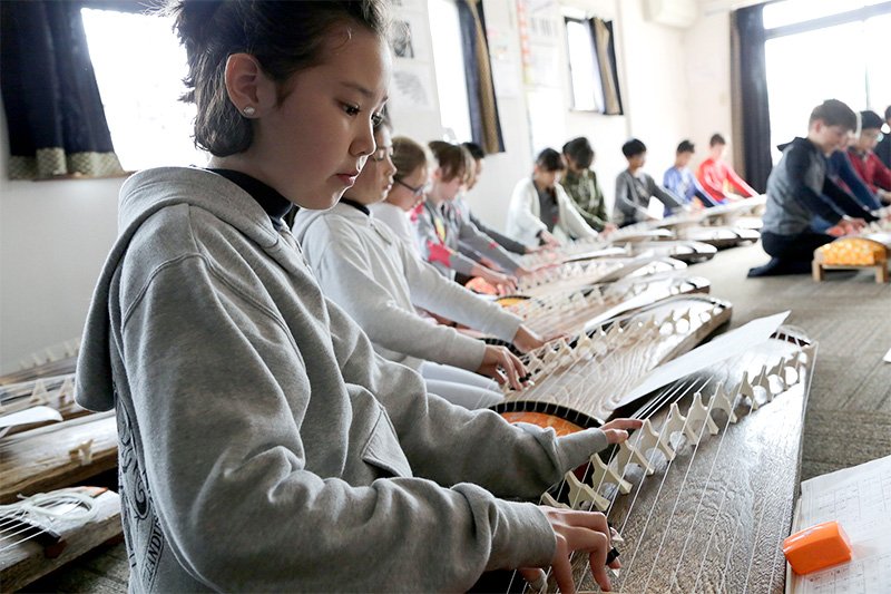 全体学生们端坐在课堂上，佩戴古筝指甲，在帕特森的指导下认真练琴