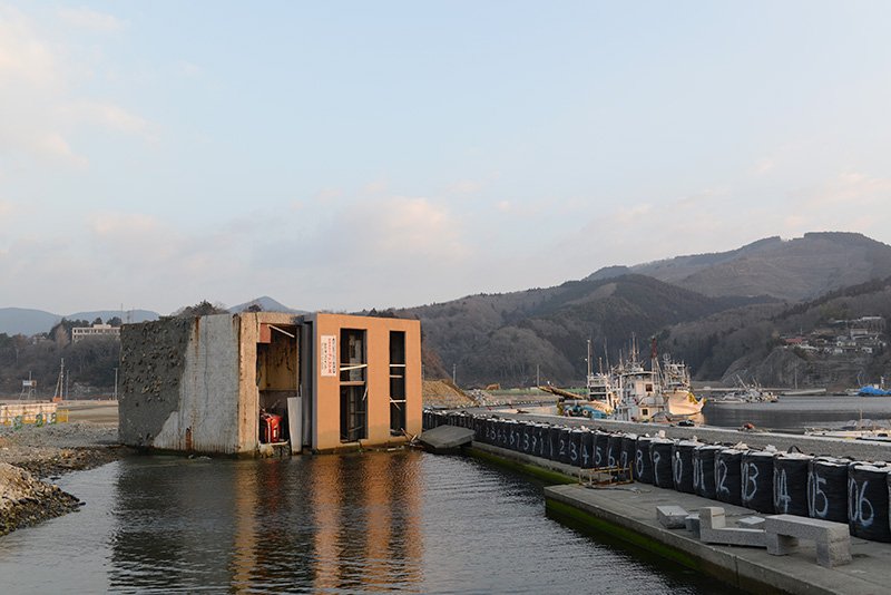 女川港では、津波に流された建物が桟橋の隣に横倒しのままになっていた。