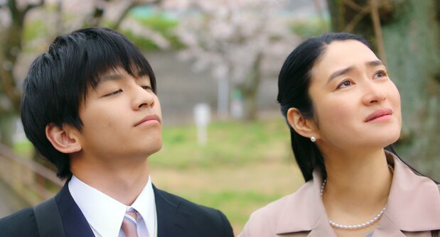 In this scene from the film, young Satoshi (Tanaka Taketo) and his mother Reiko (Koyuki) celebrate his admission to university despite losing his hearing as well as his eyesight. (© Therone/Karavan Pictures)