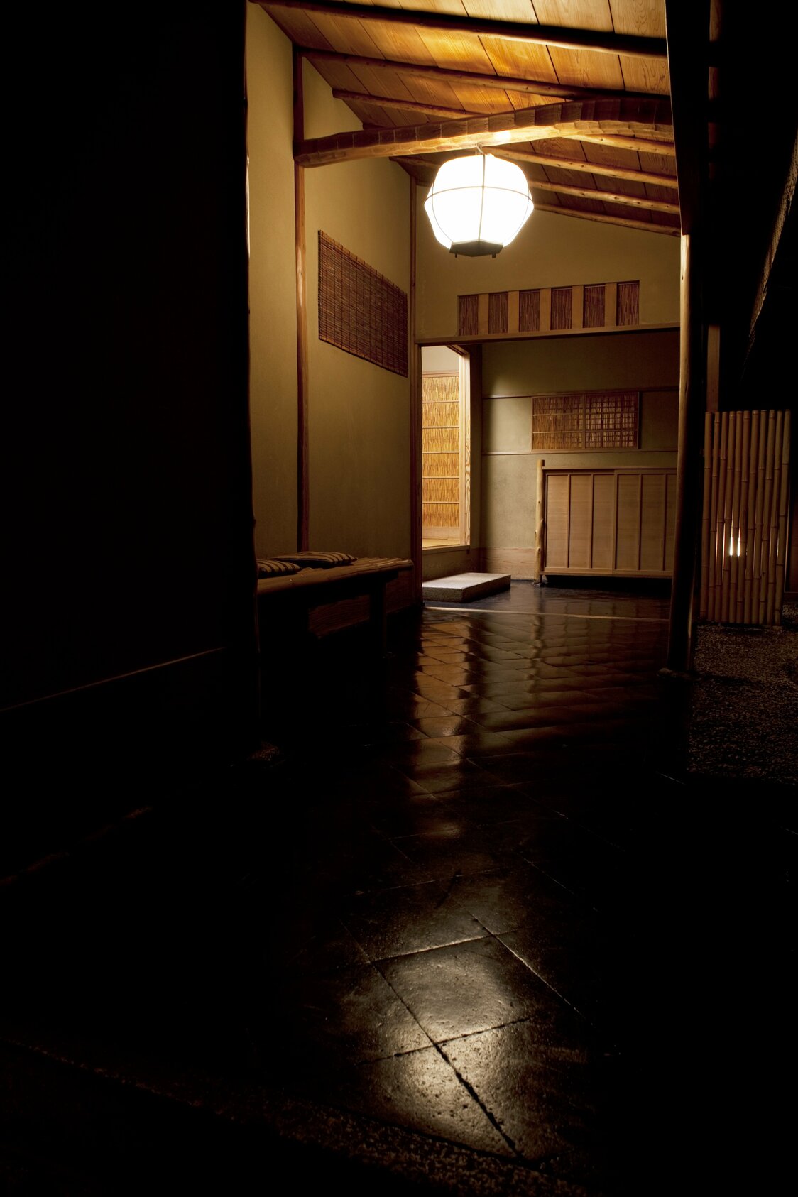 Une lumière chaleureuse vous invite au bout d’un passage éclairé par le crépuscule. Le chemin serpente dans le jardin pour mener au hall d’entrée (© Kôdaiji Wakuden)