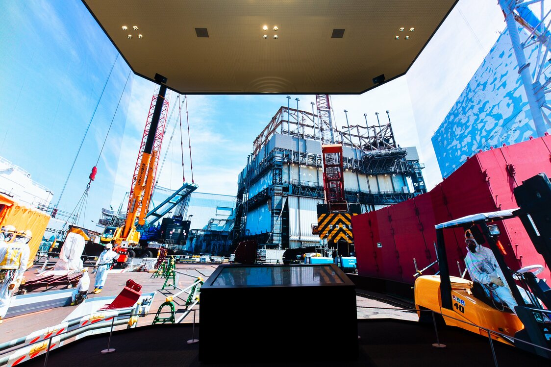 El F-Cube, con sus tres grandes pantallas cubriendo un arco de 270 grados. La escena captada por la instantánea representa un momento de las labores llevadas a cabo alrededor del primer reactor de Fukushima Daiichi, donde ocurrió una violenta explosión.