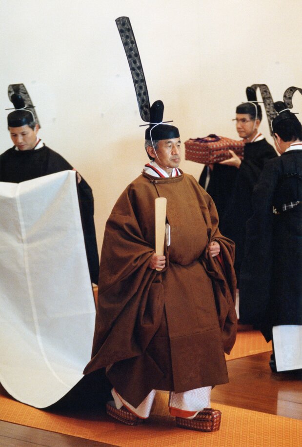 平成の「即位礼正殿の儀」で天皇陛下（現上皇さま）が身につけた黄櫨染御袍。夏は生絹（すずし）、冬は練絹で裏地は同色の平絹。桐、竹、鳳凰、麒麟（きりん）の紋様がある。右手には笏（しゃく）を持ち、足元は神職が履く浅沓（あさぐつ）に錦を貼った挿鞋（そうかい）という木製の履物を着用される＝1990年11月12日、皇居・宮殿「松の間」［代表撮影］（時事）
