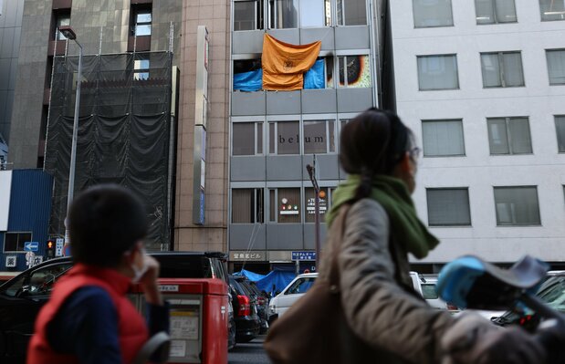 路人抬头凝视发生了纵火事件的心理诊所入住大楼（2021年12月18日，时事社）