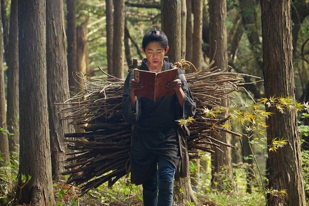 映画『二宮金次郎』より。集めた薪を背負って帰りながら読書をする少年時代の金次郎を安藤海琴が演じた(© 映画「二宮金次郎」製作委員会)
