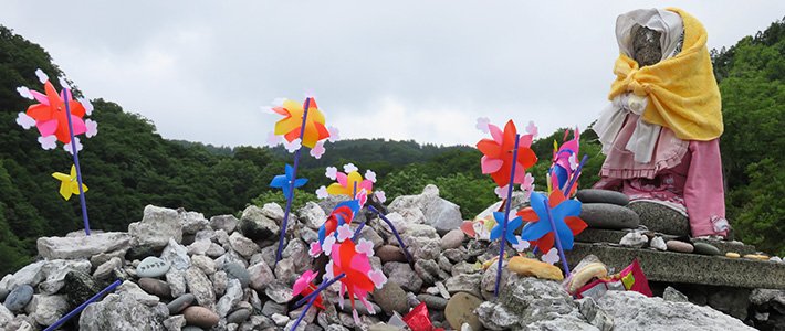 La brisa hace girar los molinetes mientras Budas de piedra ataviados con trapos vigilan un montículo de piedras cuidadosamente apiladas