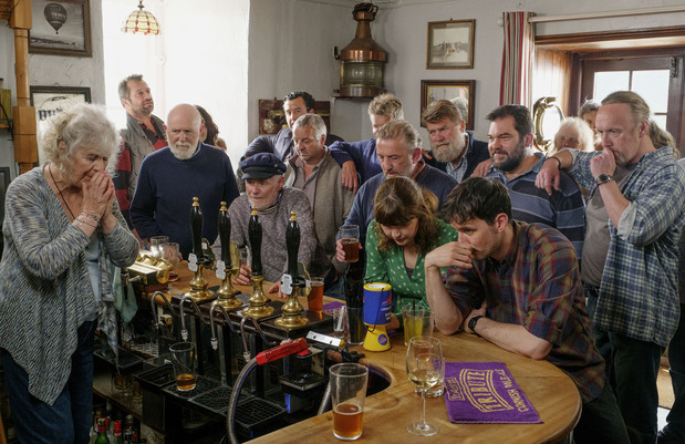 パブに集まり、全英トップチャートのラジオ番組に固唾を飲んで聴き入る村人たち © FISHERMAN FILMS LIMITED 2019