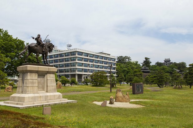 Vista del castillo de Matsue desde la plaza delante del edificio del Gobierno de Shimane. A la izquierda, una estatua ecuestre de Matsudaira Naomasa, miembro de la primera generación del clan Matsudaira.