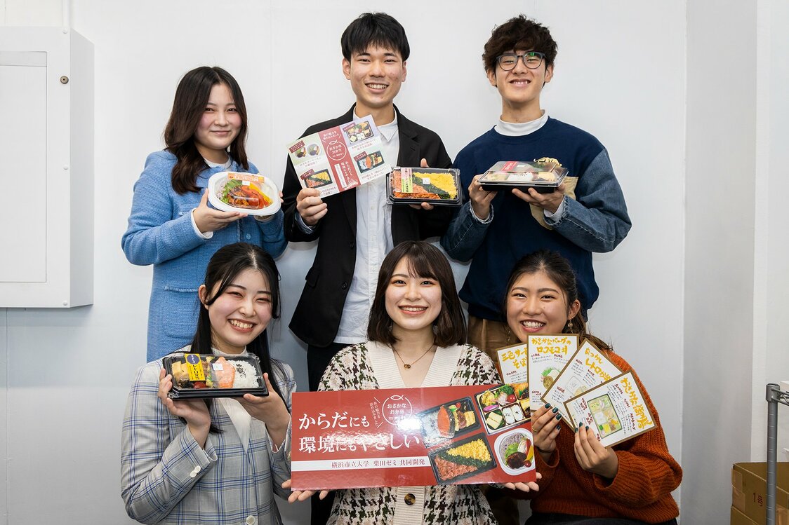 銷售日的前一天，柴田研究小組的學生們手拿製作完成的便當和宣傳單留念