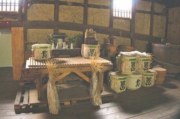 Des fûts de saké avec des gerbes de riz récolté localement sont placés devant l'autel de la brasserie.