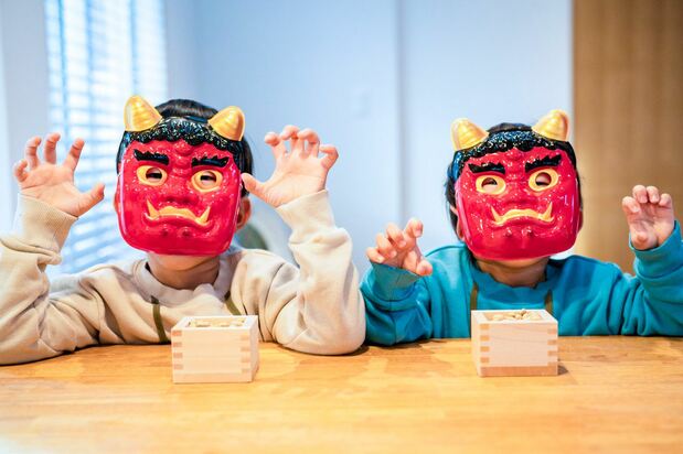 (Children wearing oni masks to celebrate Setsubun, with containers of beans ready to throw. © Pixta)