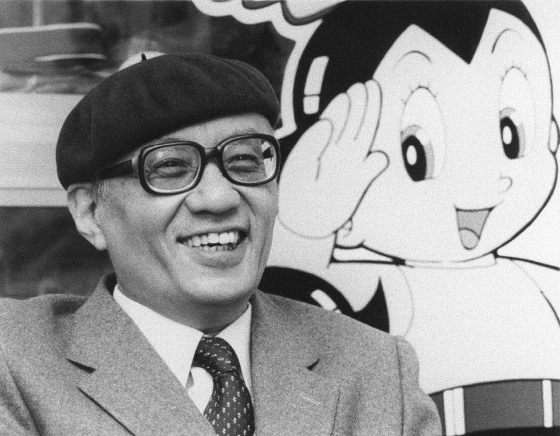 Tezuka Osamu talks in front of an image of Astro Boy in Tokyo in February 1985. (© Kyōdō; officially licensed by Tezuka Productions.)