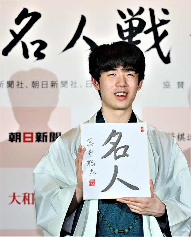 在记者会上手举签名卡的藤井聪太,他成为日本将棋最年轻的“名人”和七冠王,6月1日,长野县高山村(时事社)