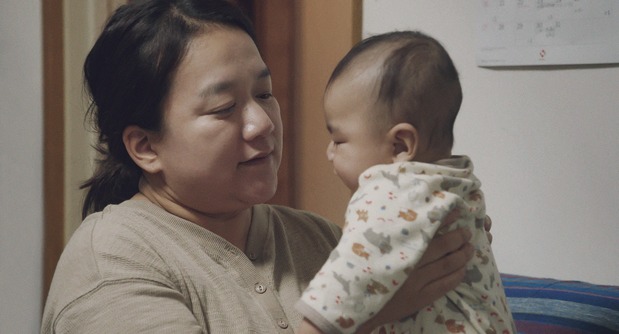 Yoshiki, el hijo menor, en brazos de Aika. Al final de la película ya camina. (© 2024 Takeshi Fukunaga/AINU PURI Production Committee)