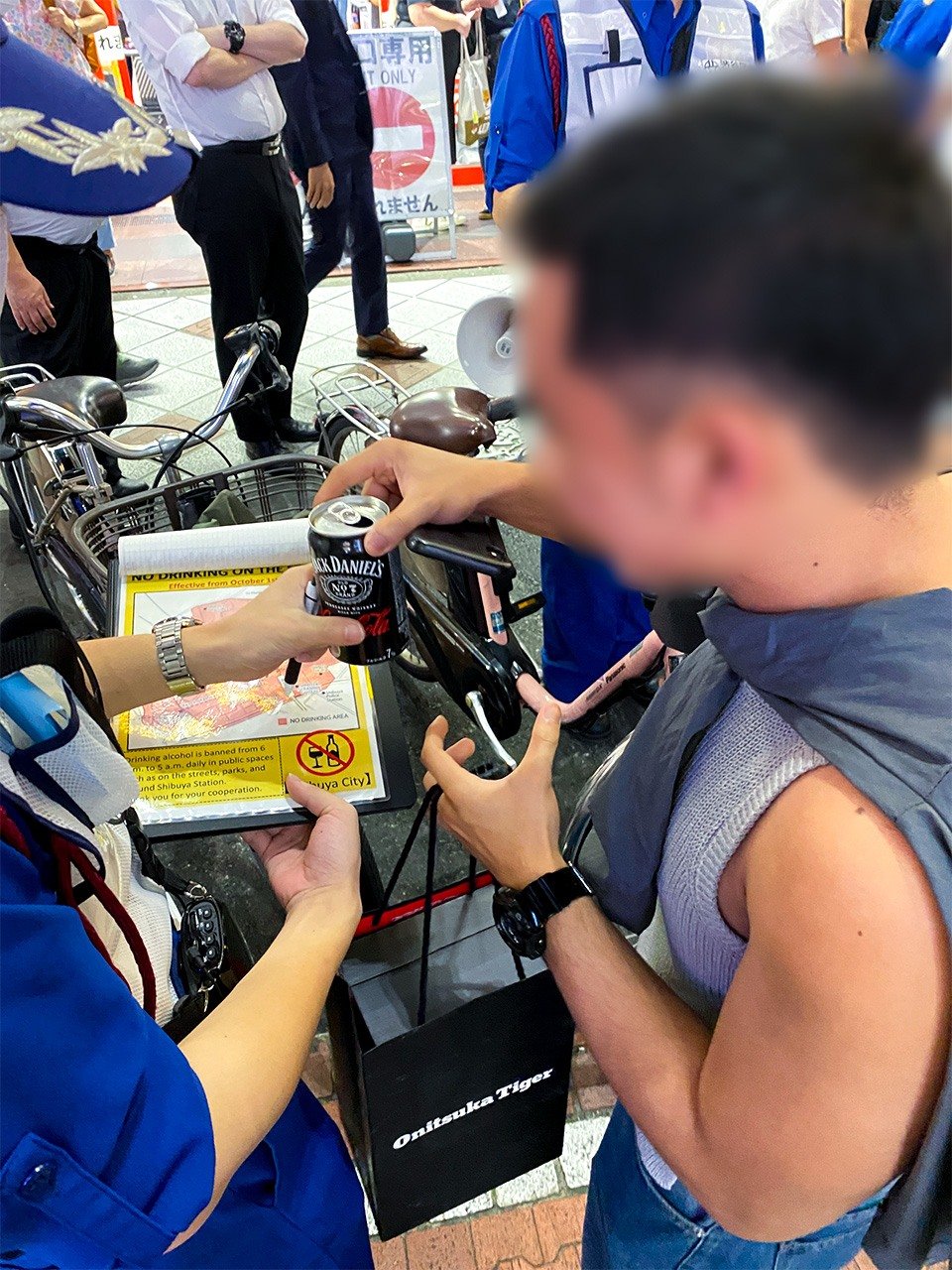 Un étranger remet volontairement la canette de cocktail qu’il buvait après avoir été informé par une patrouille de l’interdiction de boire dans la rue, près de la gare JR Shibuya, le 4 octobre 2024. (Avec l’aimable autorisation de l’auteur)
