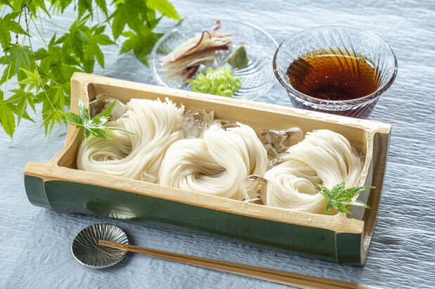 Nouilles sômen servies dans un plat en bambou accompagnées d’une sauce. (Pixta)