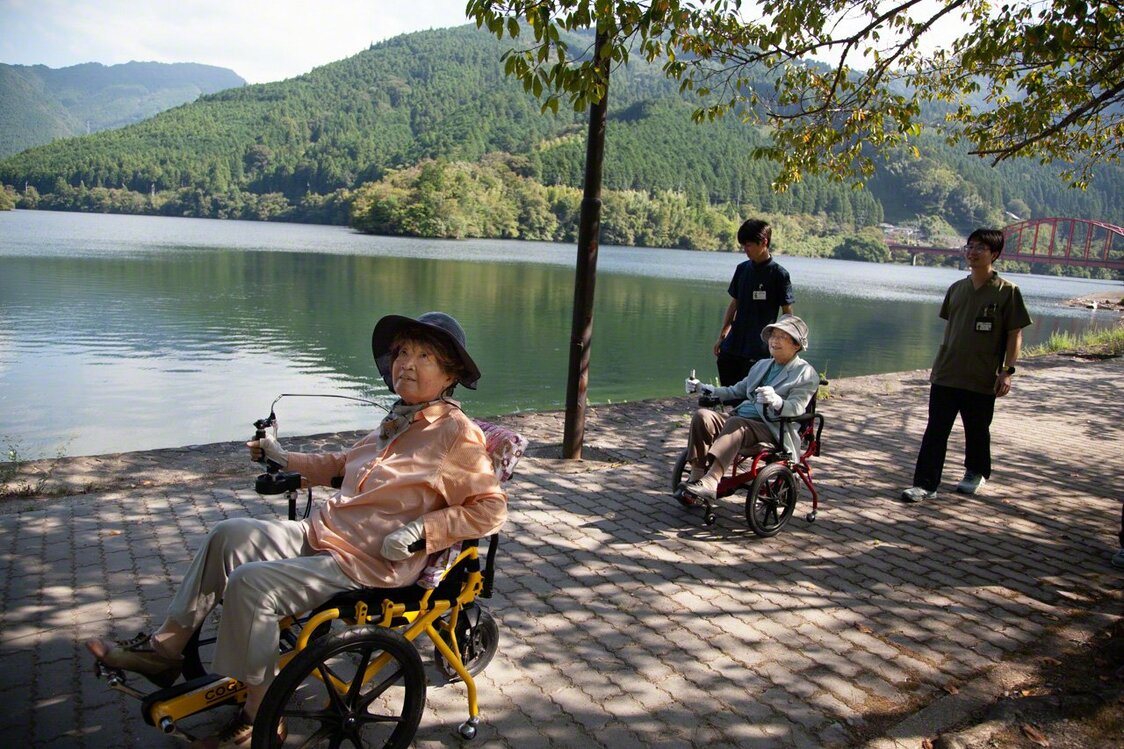 Deux amies, l’une de 94 ans et l’autre de 83 ans, prennent l’air en faisant le tour du lac en COGY. Cela fait six ans qu’elles utilisent les fauteuils à pédales. L’une d’elles raconte :« J’avais tellement mal au genou que je me rendais chez mon médecin deux fois par semaine pour des piqûres. Grâce au COGY, je n’y vais plus du tout ».