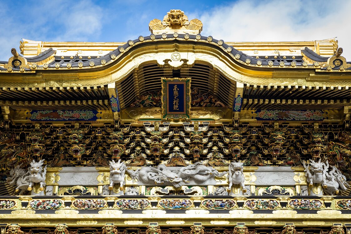 Un ogro de mirada imponente corona esta puerta de decoración pomposa. Debajo encontramos también varios dragones policromados que tienen la boca abierta en actitud amenazante. Además, en la segunda fila empezando por arriba, hay otra bestia, denominada soku, que presenta fosas nasales, pero no barba. Más abajo, en el centro, a ambos lados de Los dragones sin ojos, de color blanco, hay otros con pezuñas, como si fueran mitad caballos. (Imagen de la redacción de nippon.com)