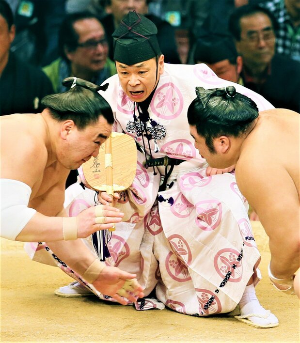 取組をさばく立行司の第40代式守伊之助(中央奥)。装束から短刀の柄がのぞく=2015年11月18日、福岡国際センター 時事